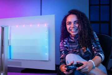 Jogadora com comando na mão ao lado de um monitor Philips Evnia com iluminação Ambiglow na traseira